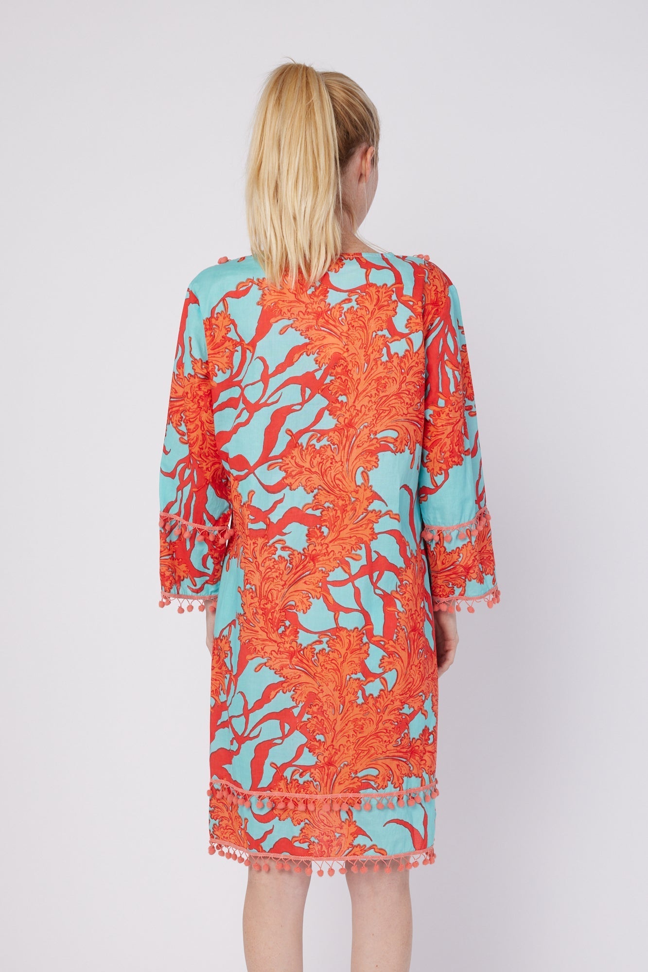 ModaPosa Pamela 3/4 Bell Sleeve V-Neck Pintuck Knee Length Dress with Pom Pom Trim in Turquoise Pink Coral . Discover women's resort dresses and lifestyle clothing inspired by the Mediterranean. Free worldwide shipping available!